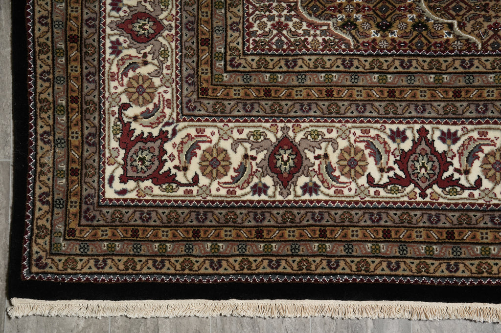 Close-up of a patterned rug with intricate designs on a gray floor.