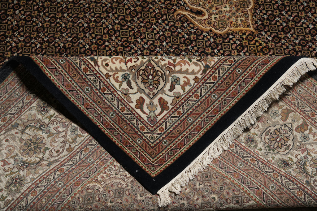 Close-up of a patterned rug with intricate designs and a black border.