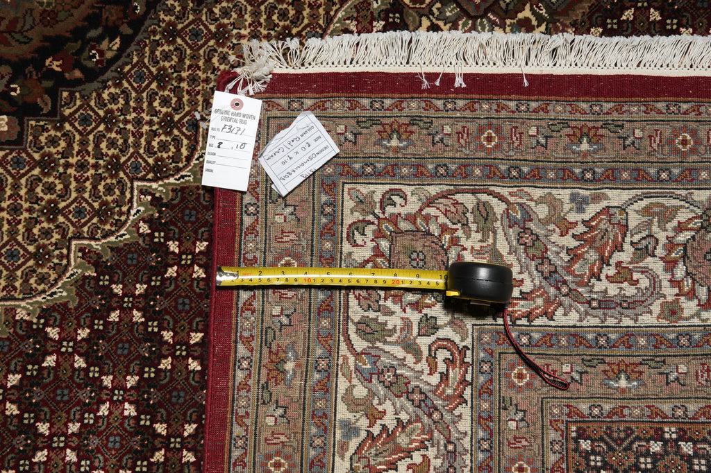 Decorative rug with a measuring tape and small container on top, surrounded by other rugs.