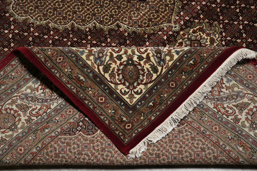 Close-up of a patterned rug with intricate designs and fringes.