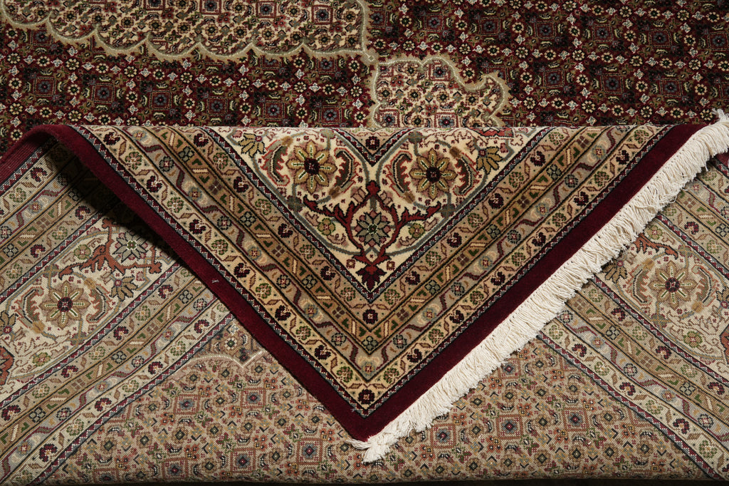 Close-up of a patterned rug with intricate designs and a red border.