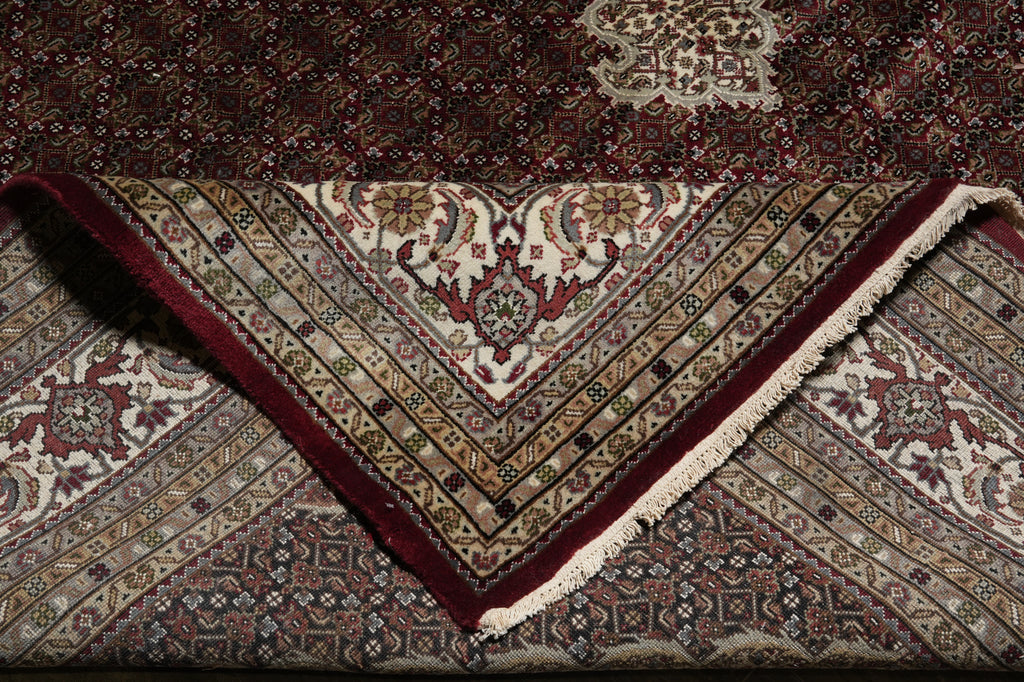 Close-up of a patterned rug with intricate designs and a fringed edge.