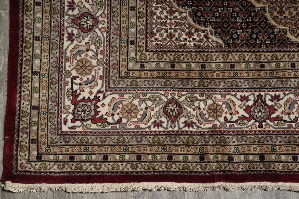 Close-up of a patterned rug with intricate designs on a wooden floor.