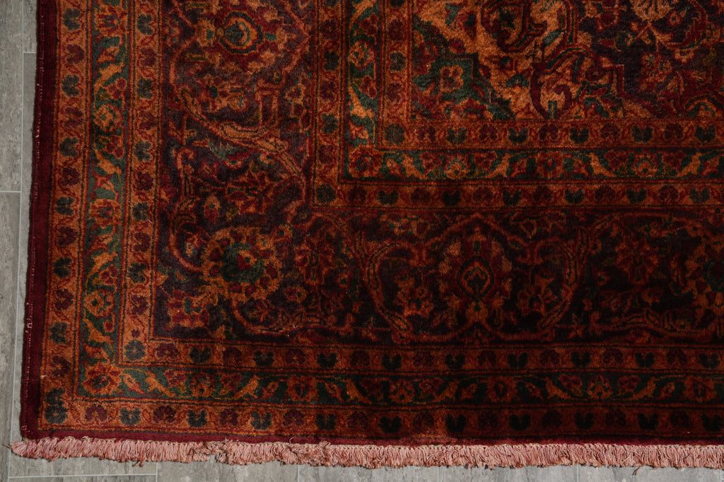 Close-up of a patterned red and black rug on a gray floor.