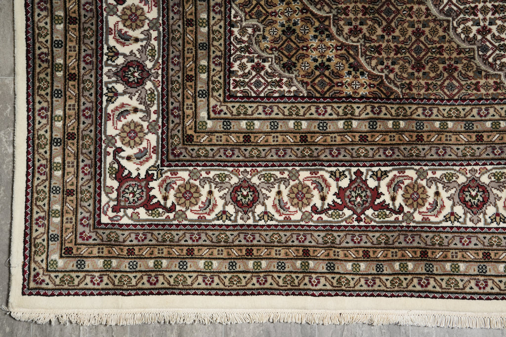 Close-up of a patterned rug with intricate designs on a gray floor.