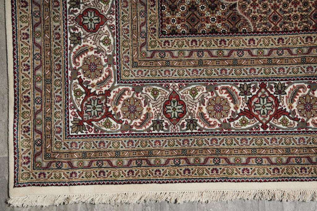 Close-up of a patterned rug with intricate designs on a concrete floor.