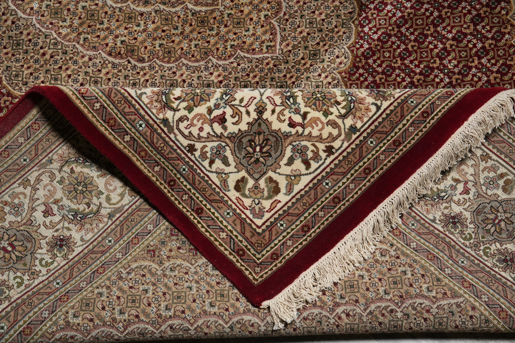 Close-up of a patterned rug with intricate designs and a red border.