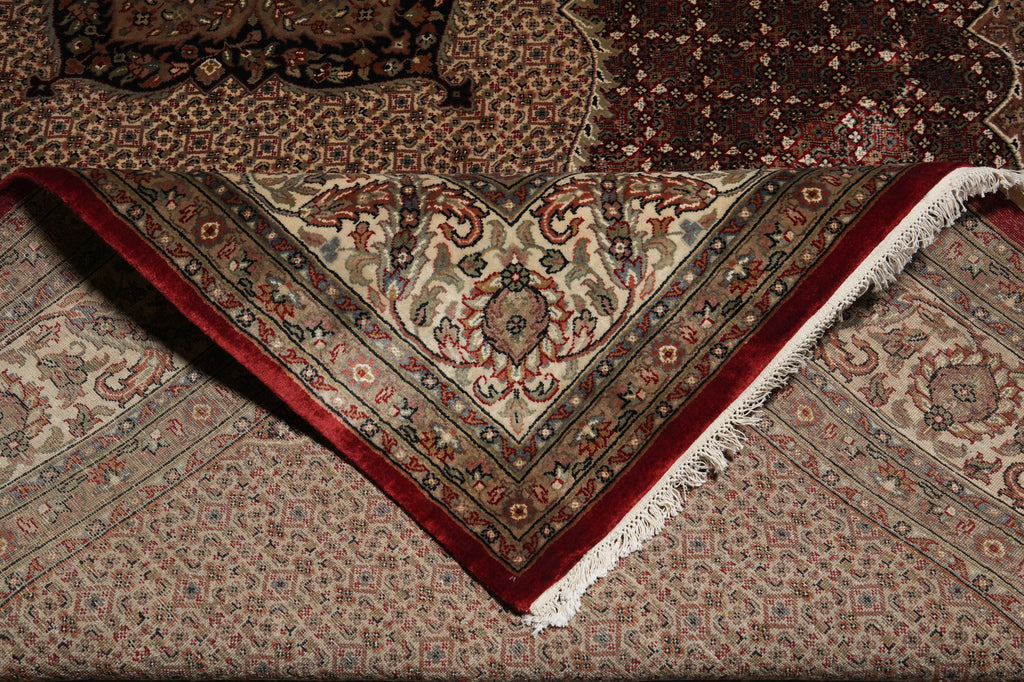 Close-up of a patterned rug with intricate designs and a red border.