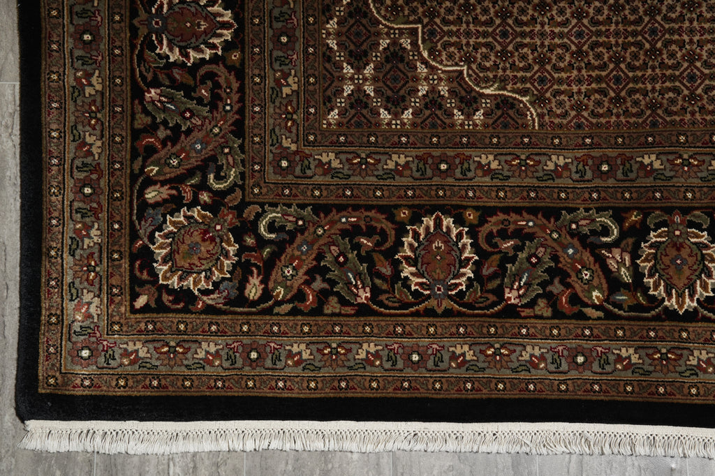 Close-up of a patterned rug with intricate designs on a gray floor.