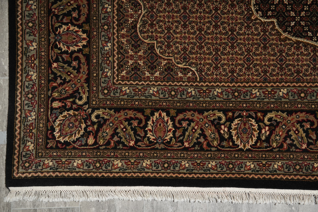 Close-up of a patterned rug with intricate designs on a gray floor.