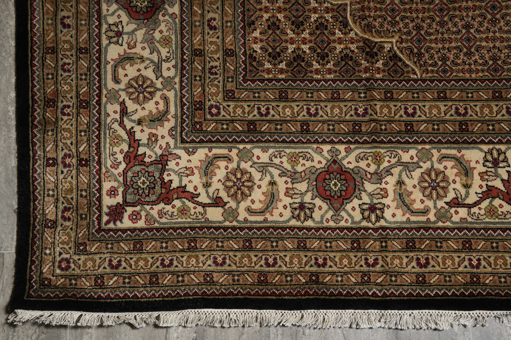 Close-up of a patterned rug with intricate designs on a concrete floor.
