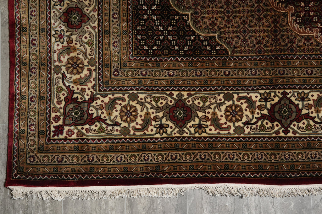 Close-up of an ornate rug with intricate patterns on a concrete floor.
