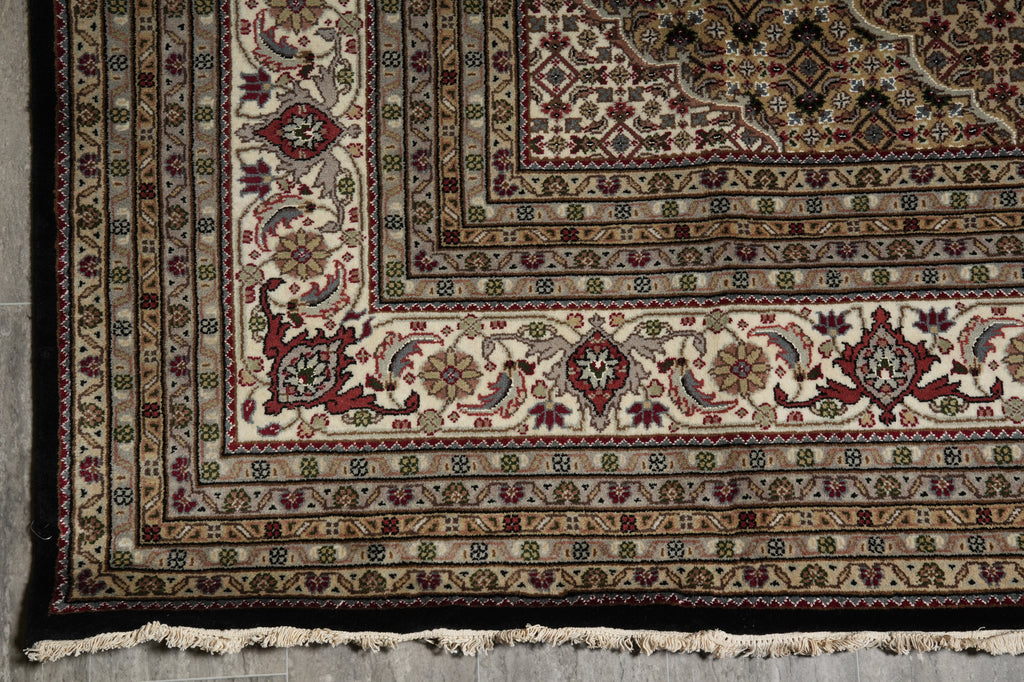 Close-up of a patterned rug with intricate designs on a wooden floor.