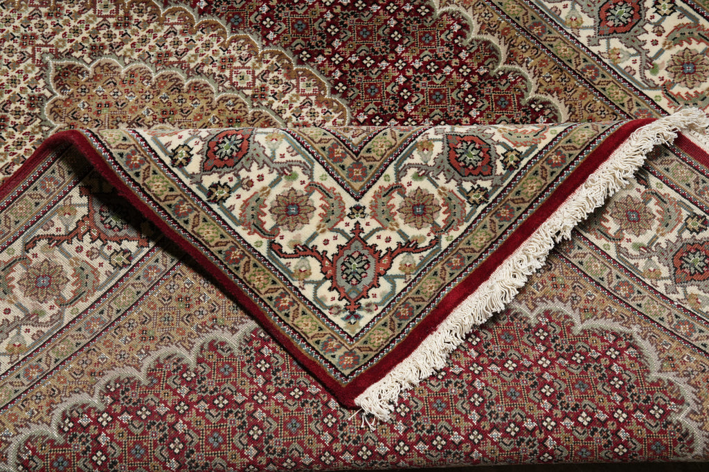 Close-up of a patterned rug with intricate designs and red border.