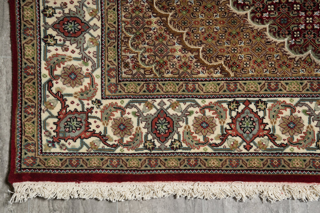 Close-up of a patterned rug with intricate designs on a gray floor.