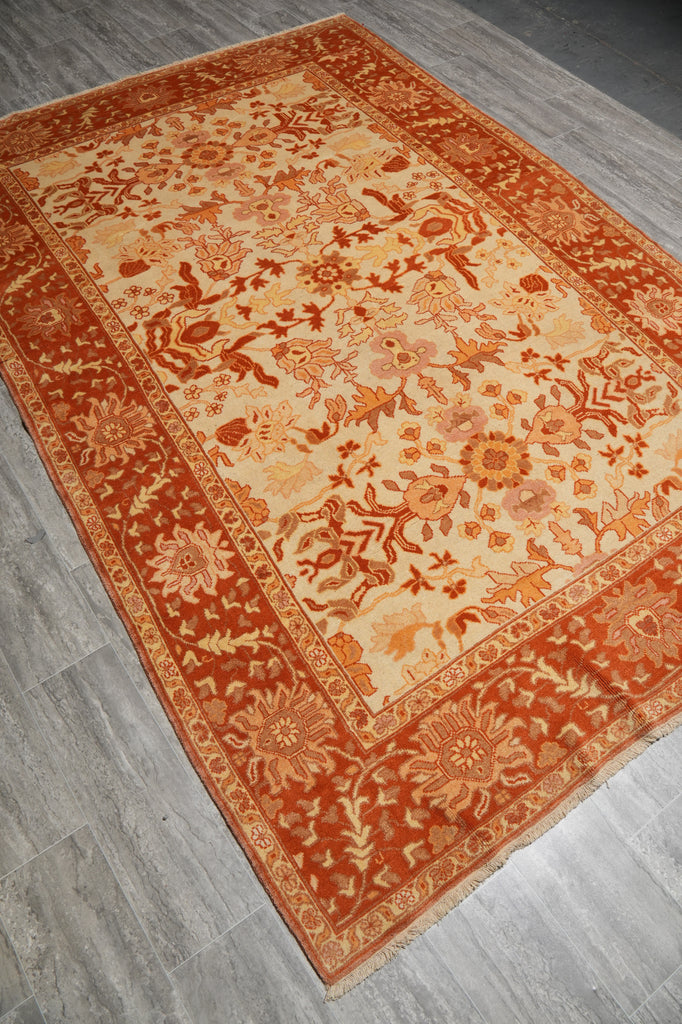 Decorative orange and beige rug on a wooden floor
