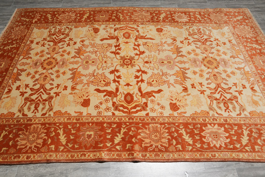 Decorative orange and beige rug with intricate patterns on a wooden floor.