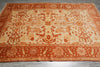 Load image into Gallery viewer, Decorative orange and beige rug with intricate patterns on a wooden floor.