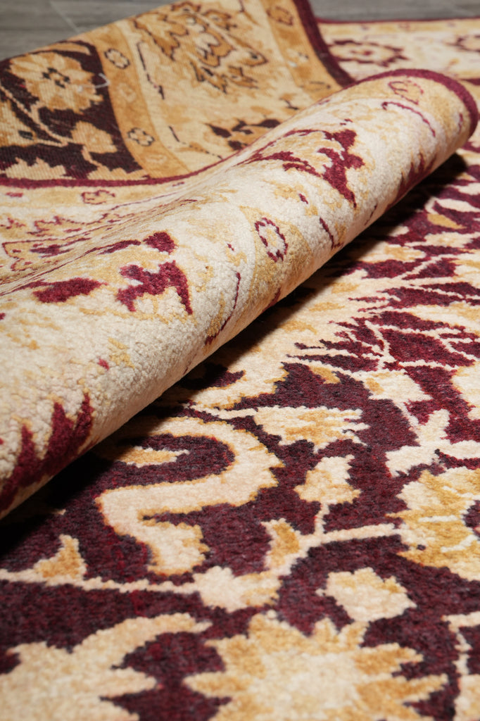 Close-up of a patterned fabric with intricate designs in red and beige.