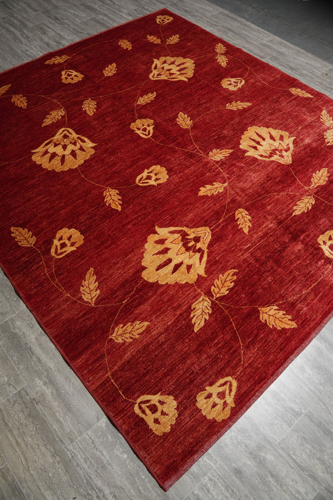 Red rug with gold leaf patterns on a wooden floor
