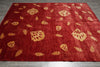 Load image into Gallery viewer, Red rug with gold floral patterns on a wooden floor