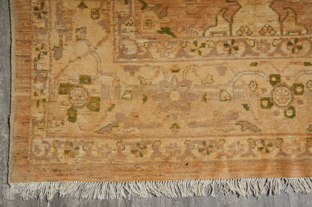Close-up of a patterned rug with visible wear and tear on a concrete floor.
