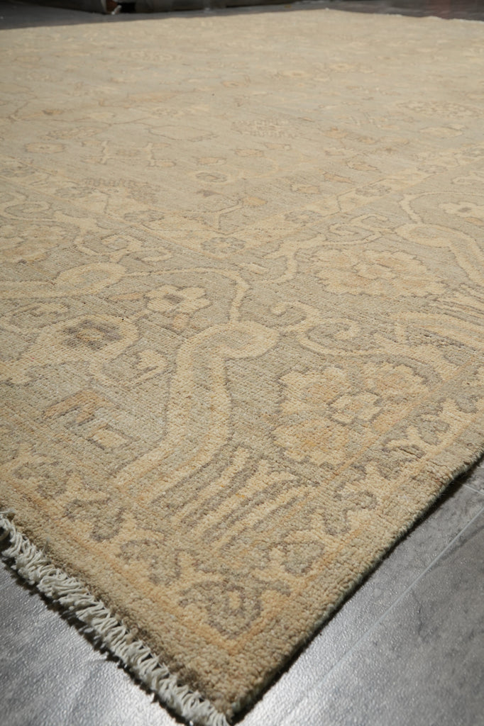 Close-up of a patterned beige rug on a gray floor.