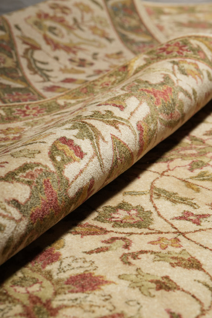 Close-up of a patterned fabric with intricate designs in red, green, and beige.