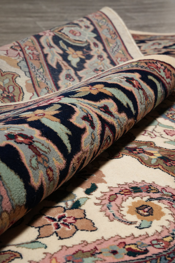Rolling up a patterned rug with intricate designs on a wooden floor.