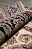 Load image into Gallery viewer, Rolling up a patterned rug with intricate designs on a wooden floor.