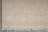 Load image into Gallery viewer, Close-up of a beige and white patterned rug with fringe on a gray floor.