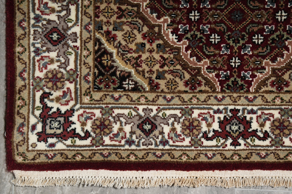 Close-up of a patterned rug with intricate designs and fringes.
