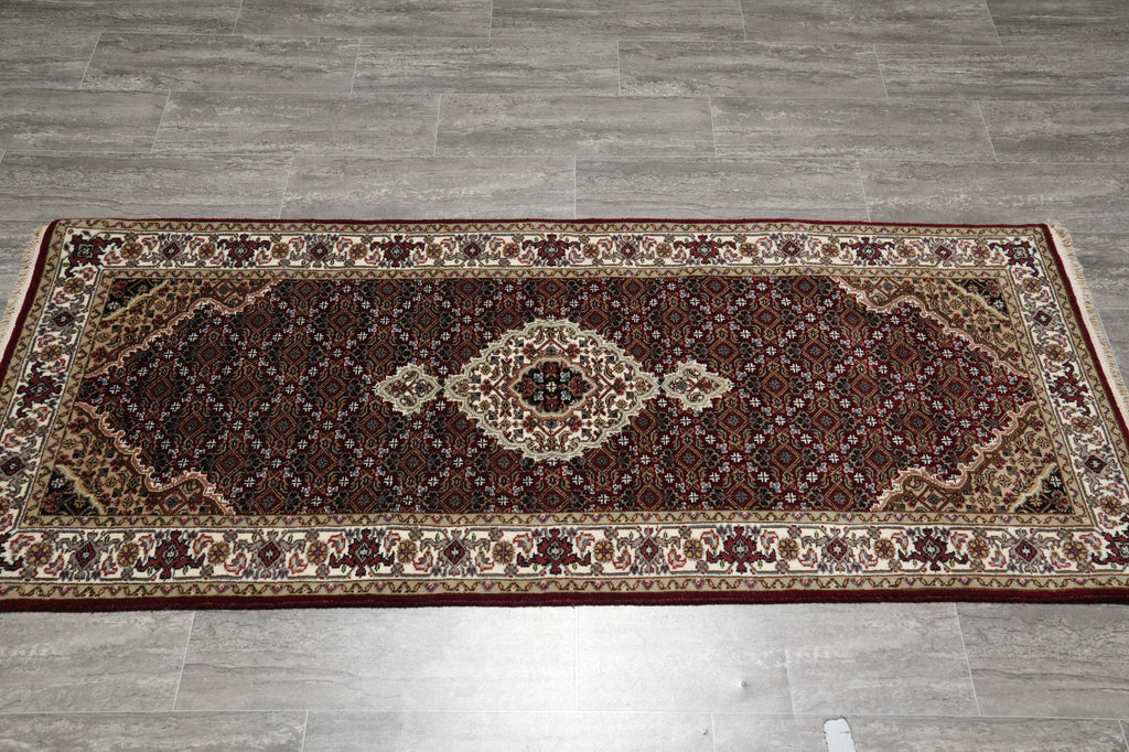 Decorative rug with intricate patterns on a gray tiled floor