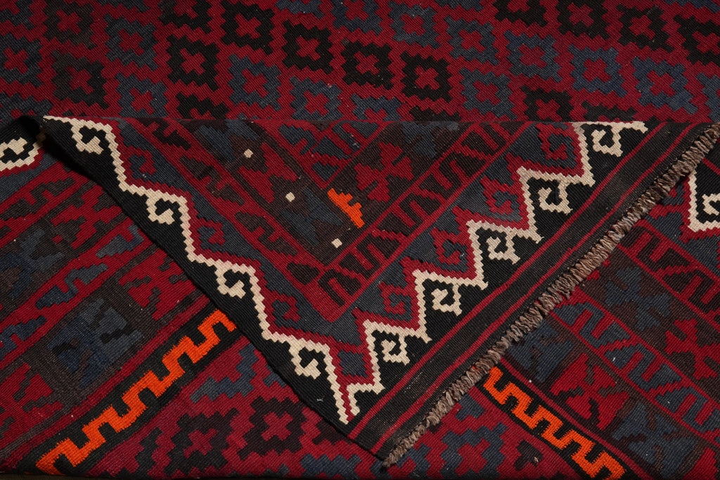 Close-up of a patterned rug with geometric designs in red, black, and white.