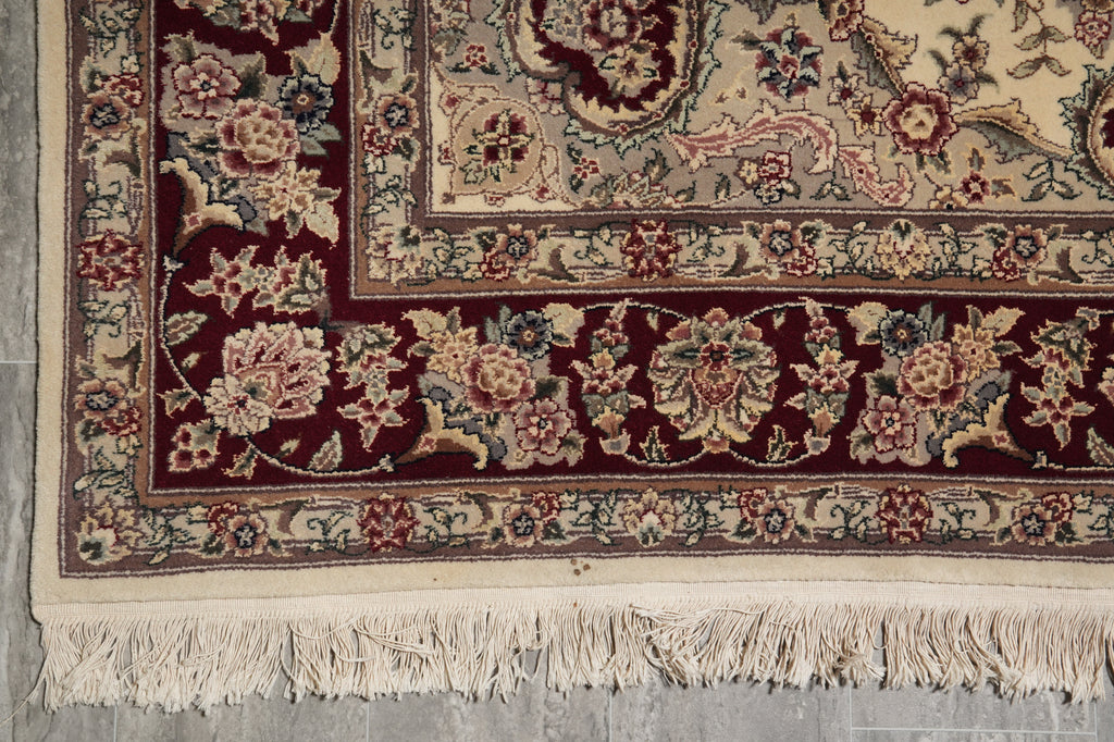 Close-up of a patterned rug with floral designs on a gray floor.