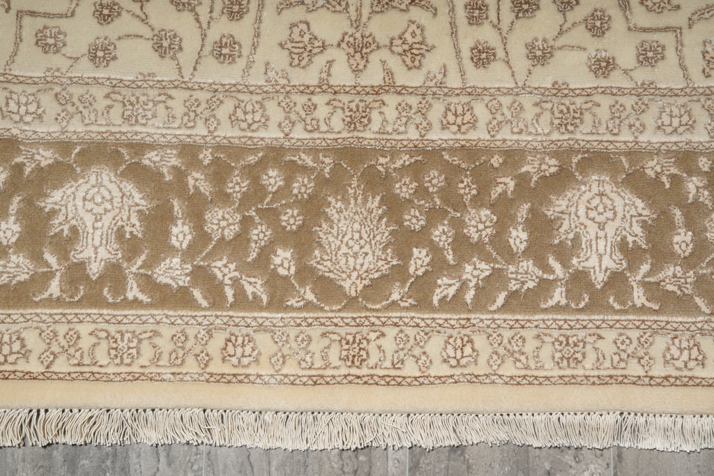 Close-up of a patterned beige rug with intricate designs on a wooden floor.