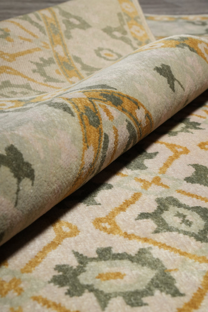 Close-up of patterned fabric with geometric design in beige, green, and yellow.