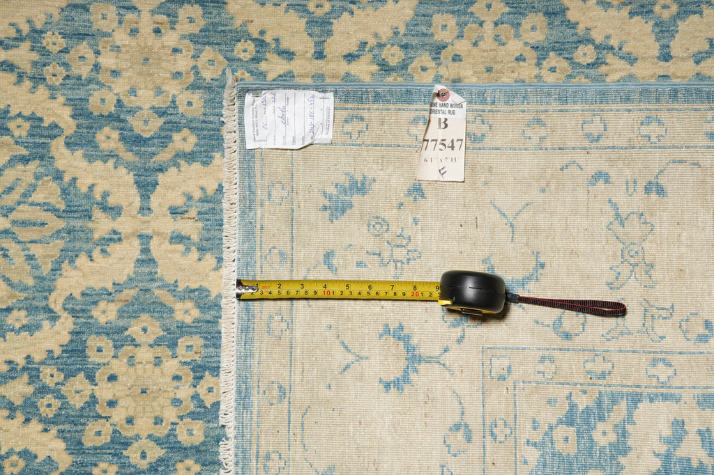 Patterned rug with a measuring tape and tags on a blue and beige floral design.