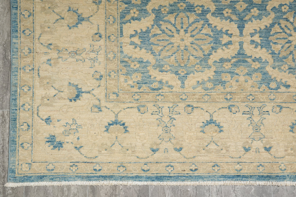 Close-up of a patterned rug with blue and beige colors on a wooden floor.
