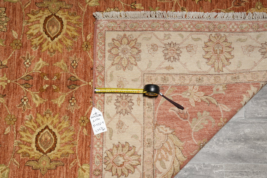 Two patterned rugs with a measuring tape on top, on a wooden floor.