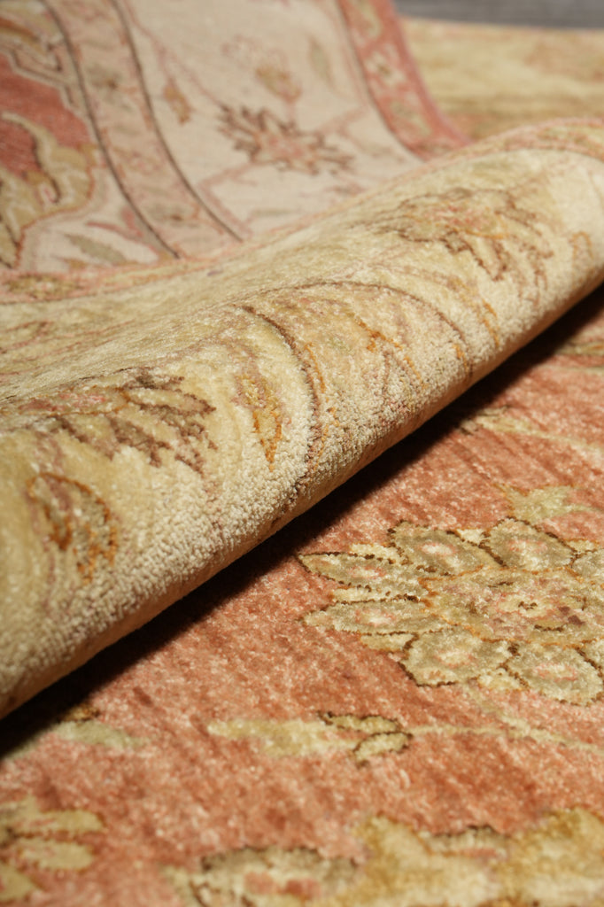 Close-up of a textured fabric with intricate patterns in shades of pink and beige.