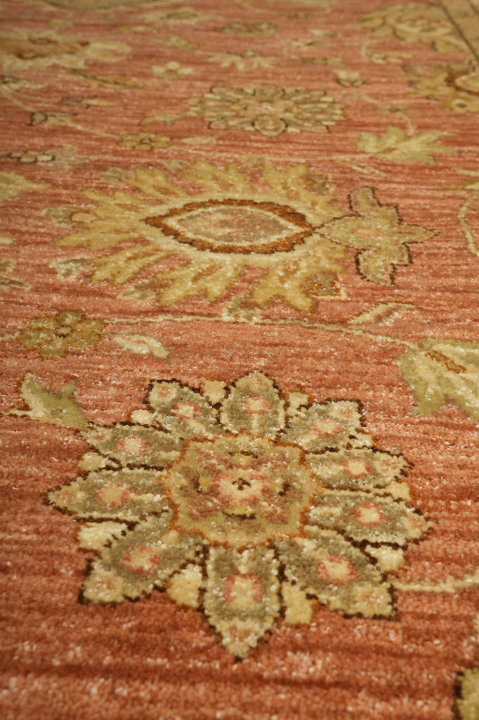 Close-up of a patterned rug with intricate designs on a red-brown background