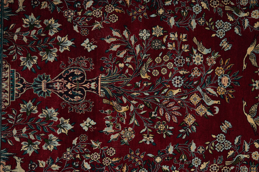 Close-up of a patterned rug with floral and bird designs on a red background
