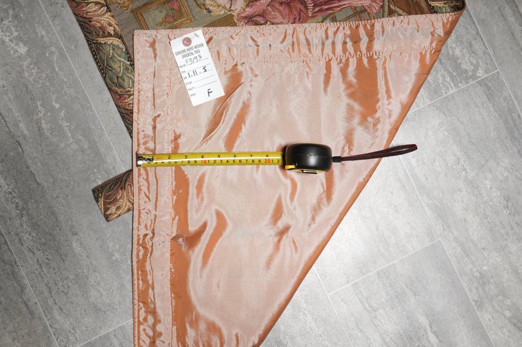 Measuring tape on a pink fabric with a label, on a tiled floor.