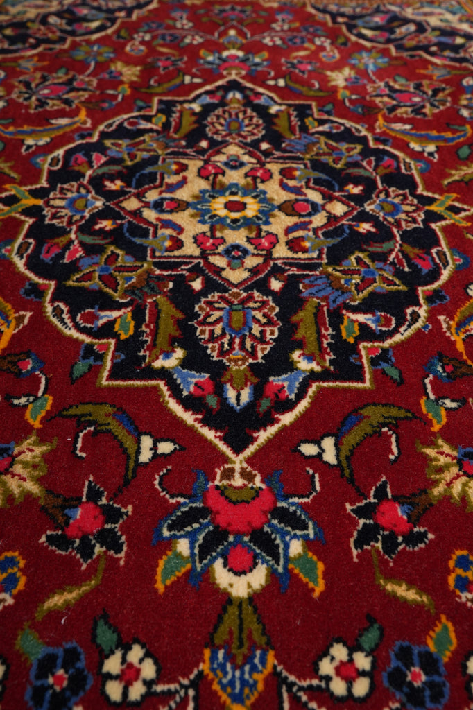 Close-up of a patterned rug with intricate designs on a red background
