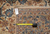 Load image into Gallery viewer, An ornate traditional area rug with a beige, blue, and rust floral pattern, shown with a yellow tape measure and a white tag on a flat surface.
