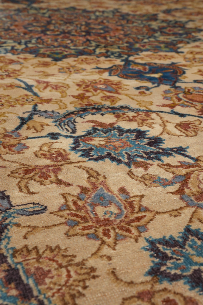 Close-up of an ornate area rug with a traditional floral pattern in beige, blue, brown, and rust tones.