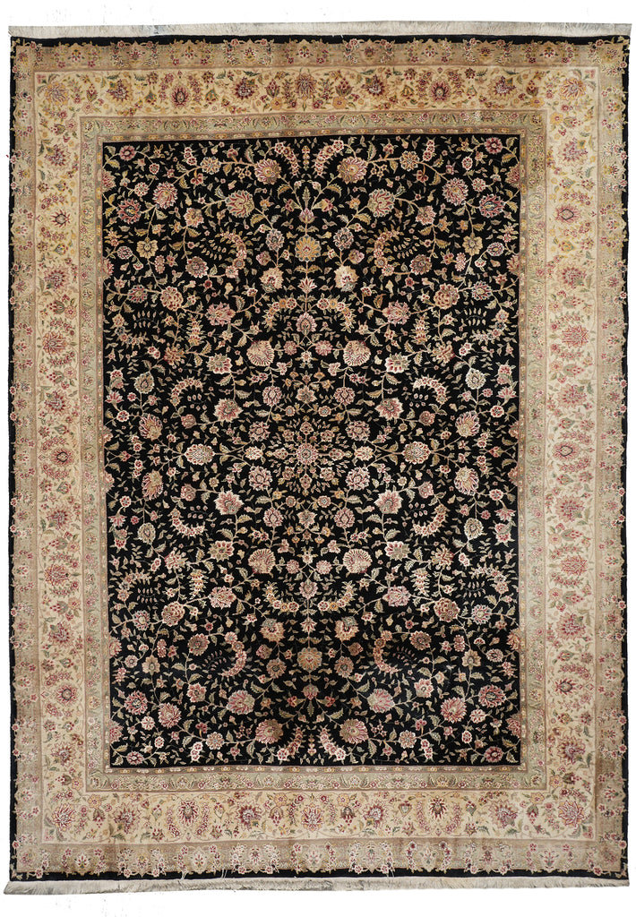 A rectangular traditional area rug with an intricate floral pattern, featuring a dark central field surrounded by a wide beige and pink ornamental border.