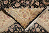 Load image into Gallery viewer, A close-up of a folded floral area rug showing two patterned sections: one cream and beige with pink and gold floral motifs and white fringe, and one black with matching floral patterns in pink, beige, and green.