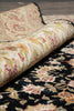 Load image into Gallery viewer, A close-up of a folded patterned rug showing two distinct sections: one with a black background and cream floral motifs, and another with a beige background and multicolor floral/paisley patterns.
